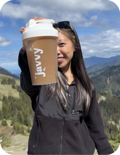 Customer on a mountain trail holding up a Javvy shaker bottle