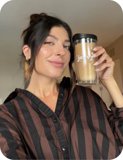 Customer smiling with a Javvy tumbler of iced protein coffee