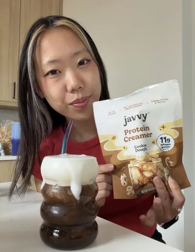Customer with a bag of Javvy Protein Creamer and an iced coffee