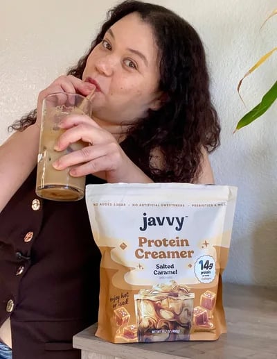 Customer sipping an iced coffee next to a bag of Salted Caramel Protein Creamer