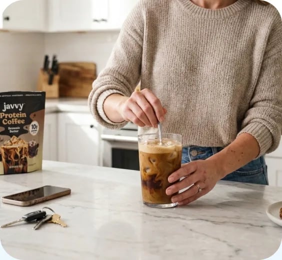 Woman stirring an iced protein coffee at the kitchen counter