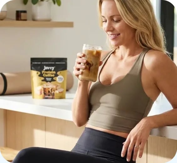 Woman in workout clothes holding an iced protein coffee