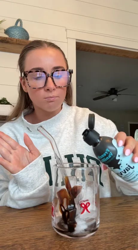 Customer pouring French Vanilla Coffee Concentrate over ice