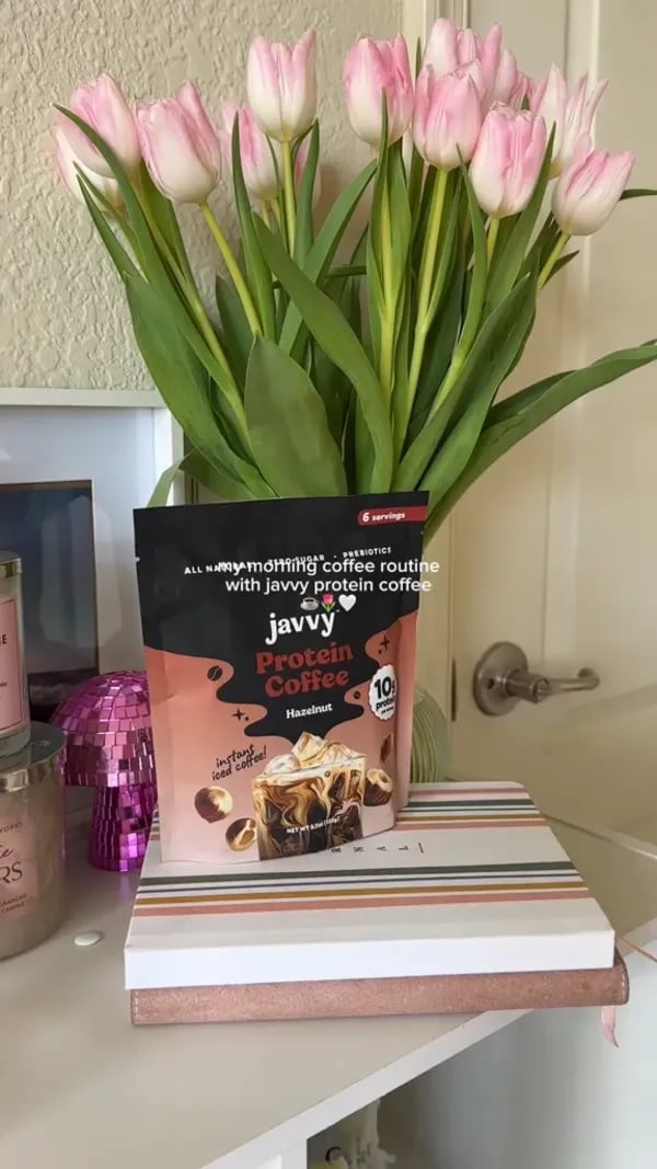 Hazelnut Protein Coffee bag next to a vase of tulips