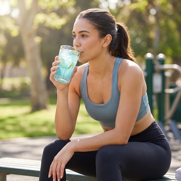 Woman drinking a protein refresher outdoors before a workout