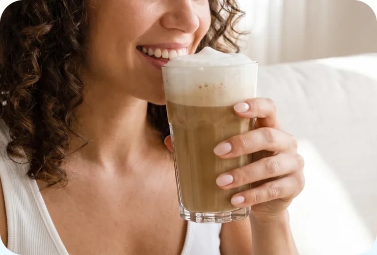 Woman smiling over a creamy iced coffee