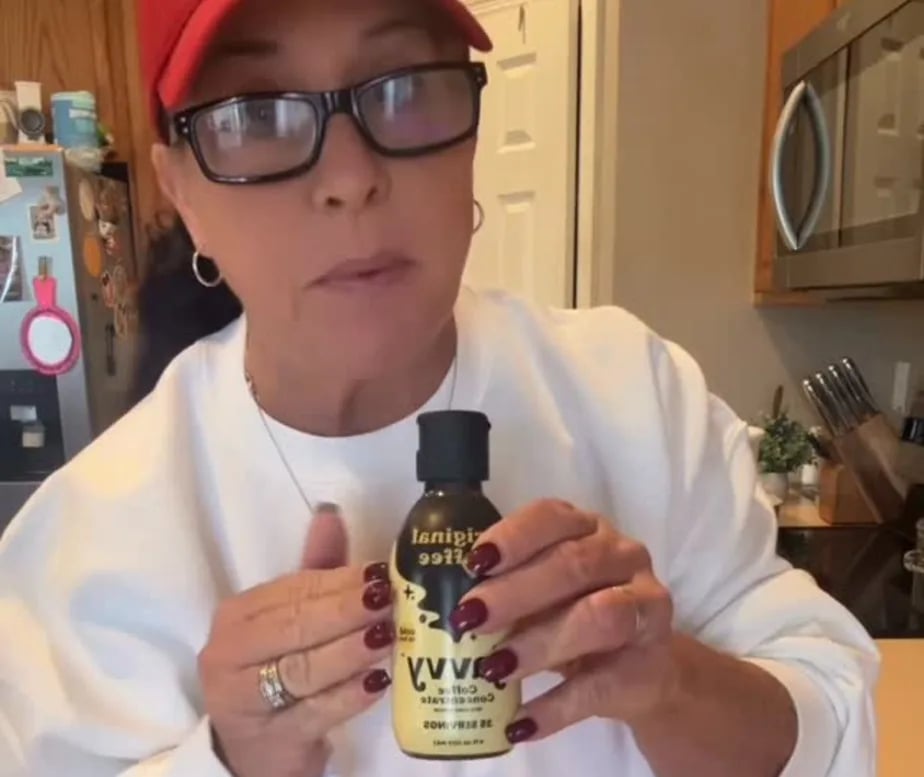 Customer in her kitchen holding a bottle of Javvy Coffee Concentrate