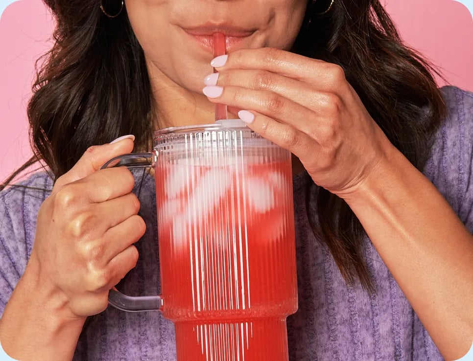 Woman sipping a Javvy Protein Refresher through a straw
